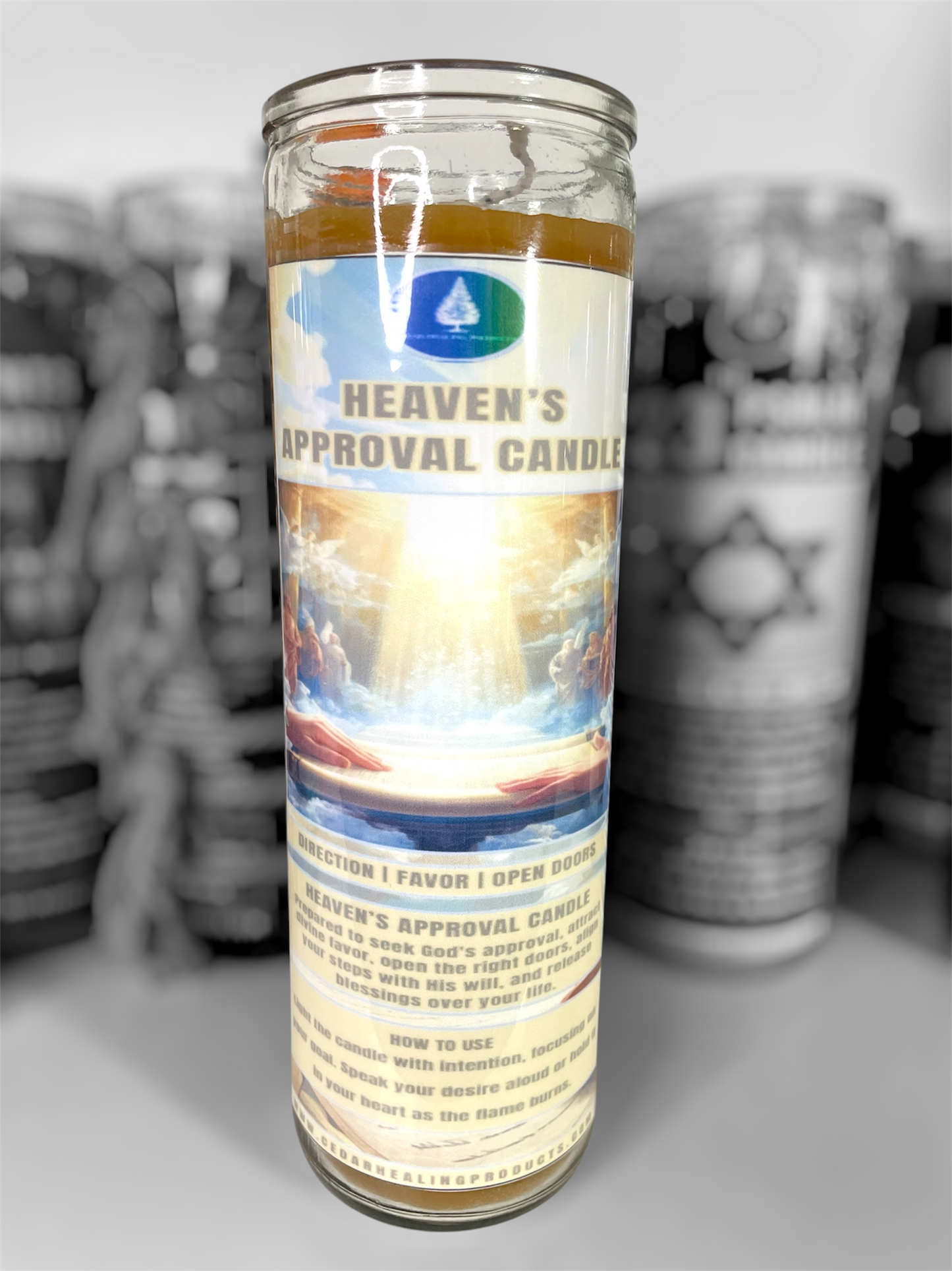 A tall glass prayer candle labeled 'Heaven's Approval Candle' with a colorful religious label, shown in front of a blurred row of similar candles.