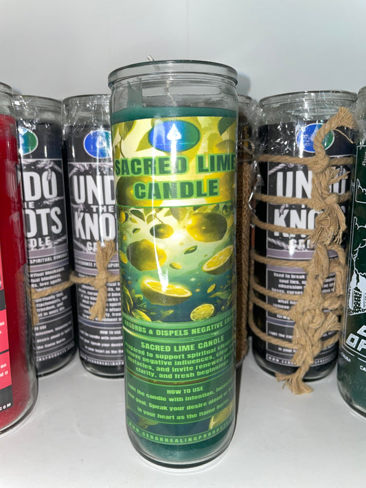 A tall glass jar candle labeled 'Sacred Lime Candle' with a green and yellow tropical lime graphic label, wrapped in natural twine, standing in front of several other dark scented candles.