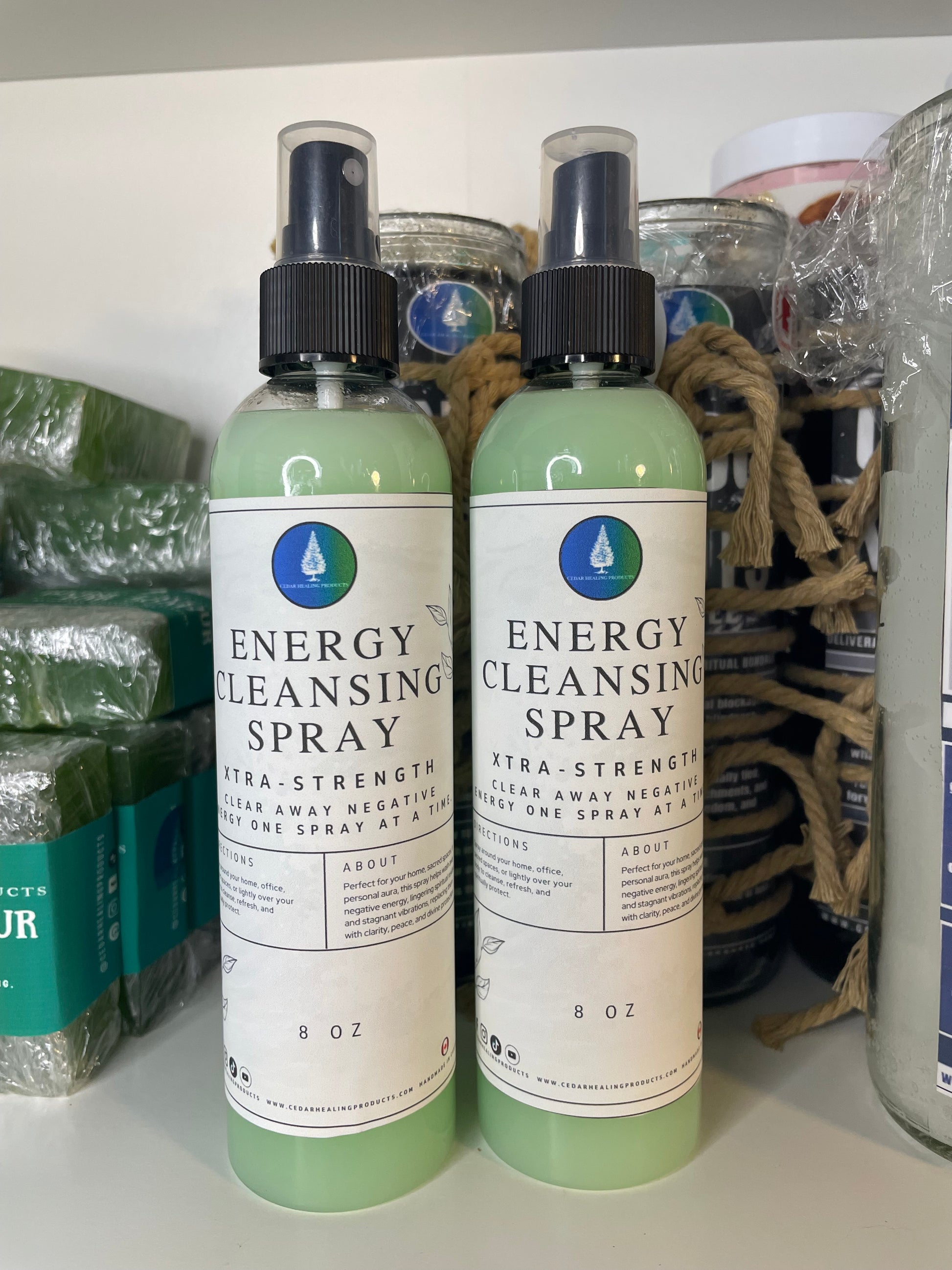 Two bottles of 'Energy Cleansing Spray' on a white surface with packaging materials.
