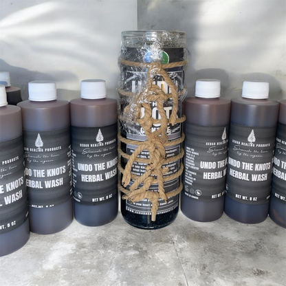 Bottles of 'Undo the Knots Herbal Wash' with a central bottle wrapped in rope on a gray surface.